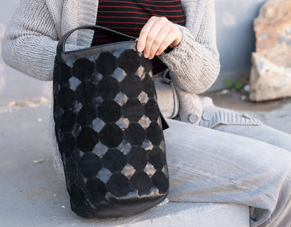 Person holding a black textured bag outdoors