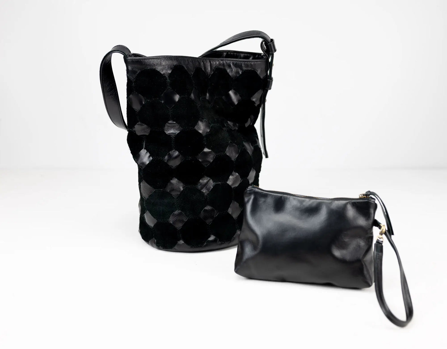 Two black leather bags, one with a textured pattern and the other a plain pouch, on a white background.
