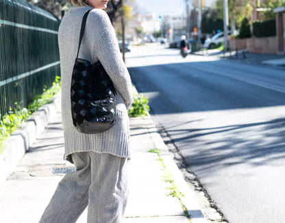 Person walking on a sidewalk with a patterned bag in an urban setting