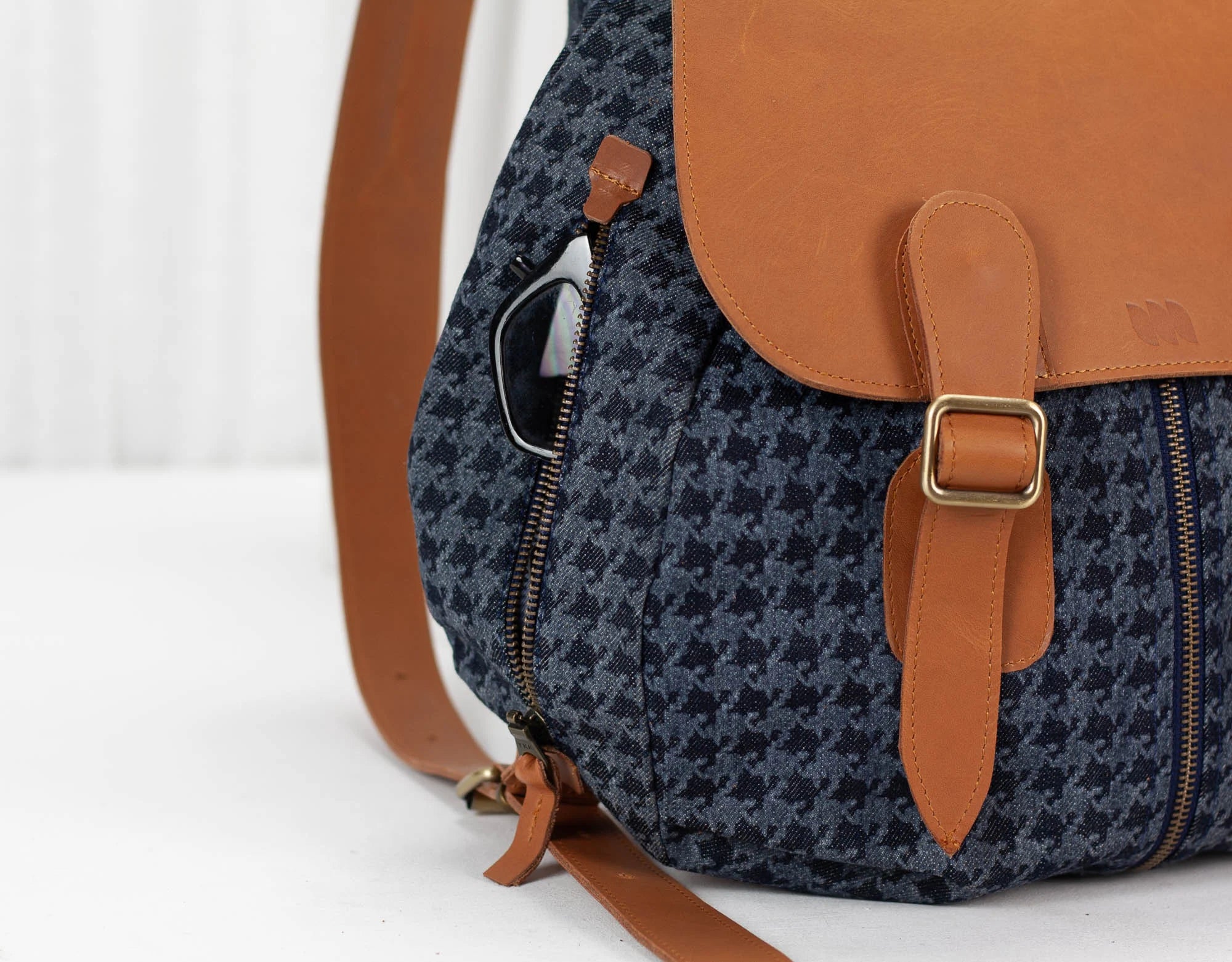Backpack with blue pattern and brown leather straps on a white background
