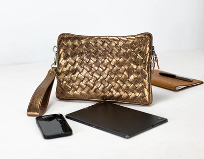 Gold woven clutch bag with phone, tablet, and notebook on a white background