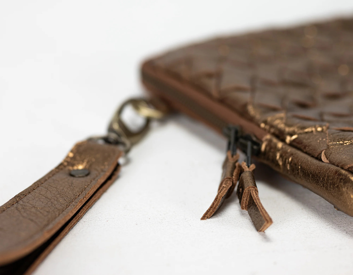 Brown leather clutch bag with strap on a white background