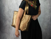 Person holding a gold woven handbag 