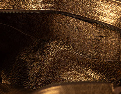 Close-up of the interior lining of a metallic bronze pebbled leather bag, showing the debossed brand name &