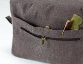 Close-up of a brown textured bag with a zipper pocket containing a pen  