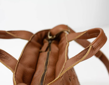 Close-up of a brown leather bag with a zipper on a white background