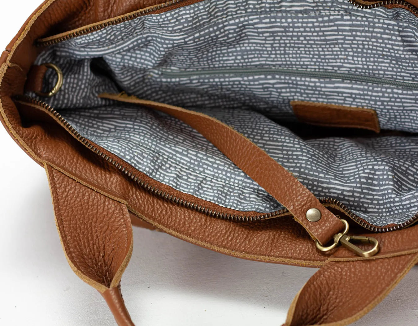 Brown leather bag with gold zipper on a white background