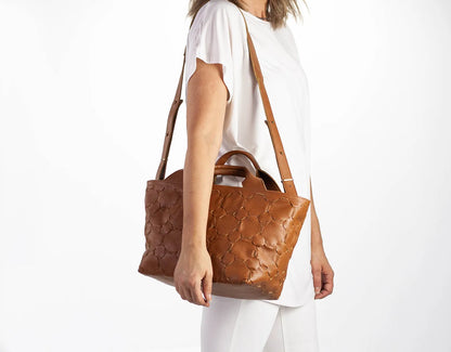 Person holding a brown textured handbag on a white background