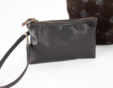 Black leather clutch bag with a strap on a white background