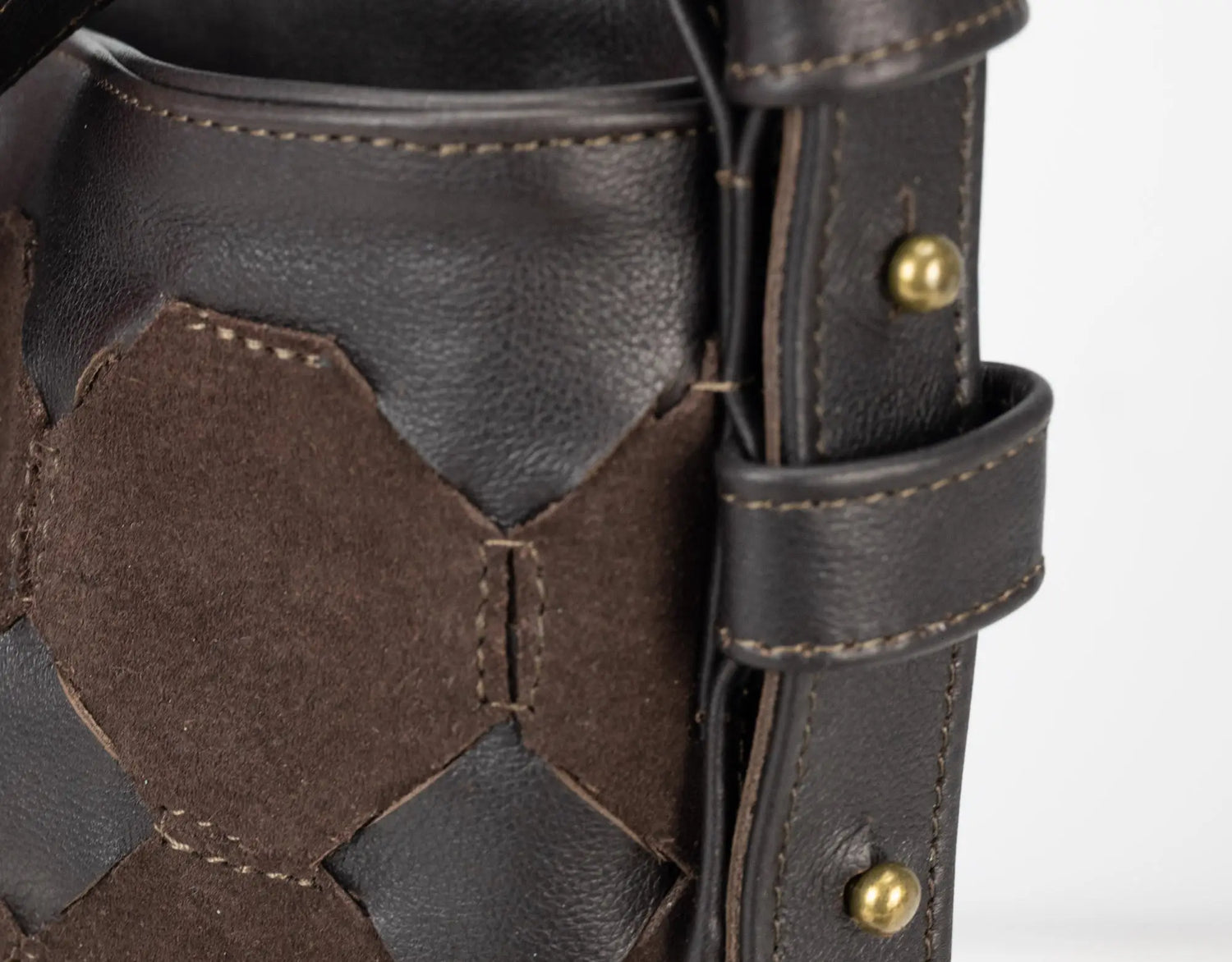 Close-up of a brown leather glove with hexagonal pattern and gold button on a white background