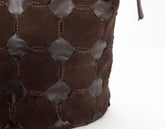 Close-up of a brown woven leather handbag on a white background