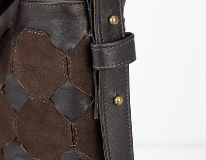 Close-up of a brown leather outfit with geometric pattern and gold buttons on a white background