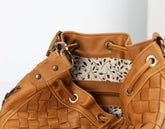 Brown leather handbag with floral interior lining on a white background