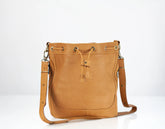 Tan leather handbag with drawstring on a white background