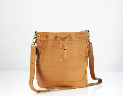 Tan leather handbag with drawstring on a white background
