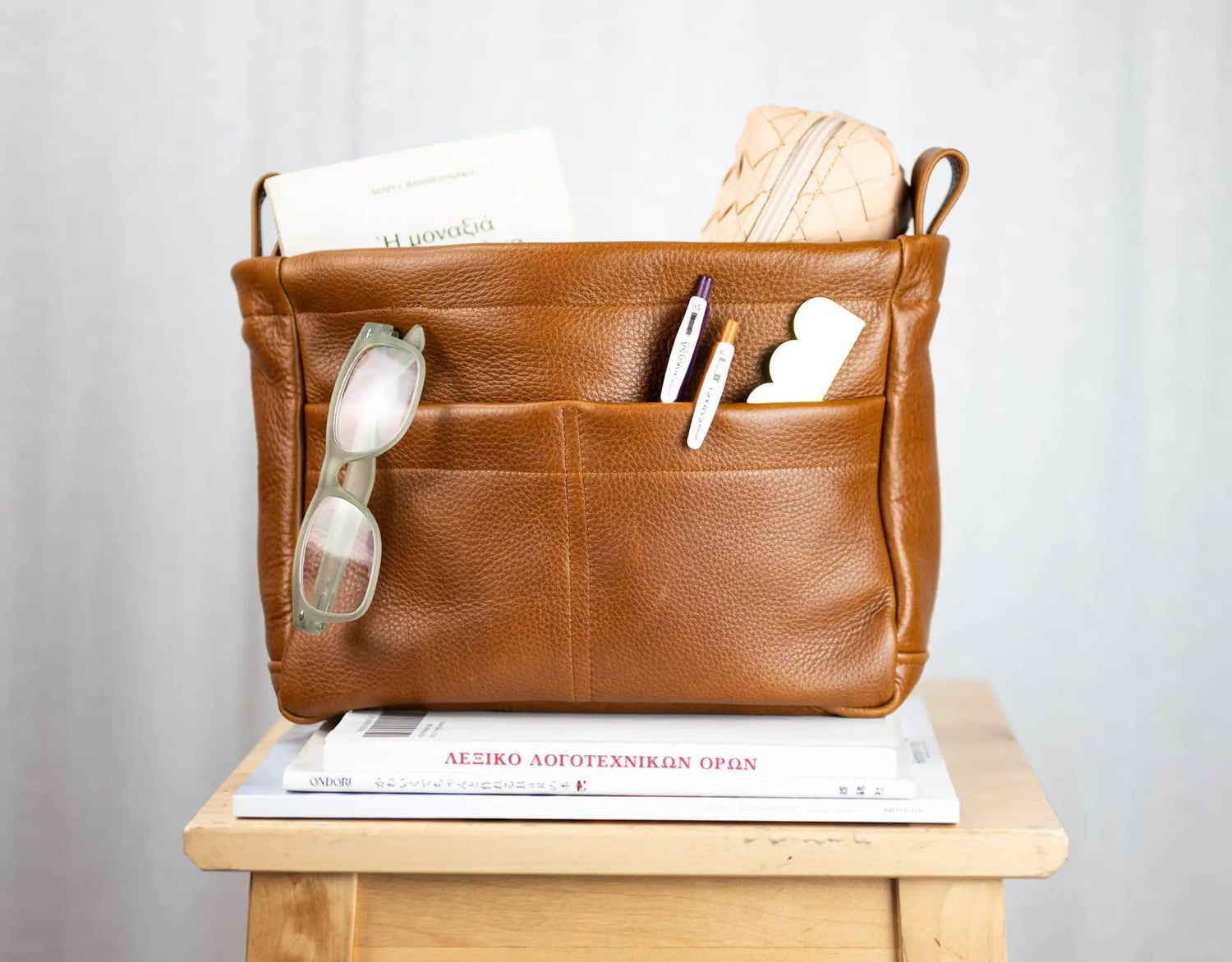 Brown leather bag with compartments on a wooden surface