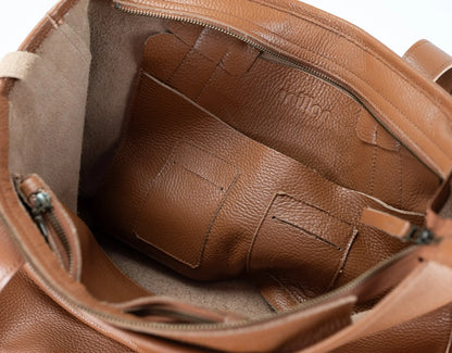 Close-up of the interior of a brown pebbled leather bag, showing the lining, zipper, and interior card slots.