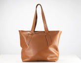 A medium brown leather tote bag with dual shoulder straps, displayed against a clean white background.