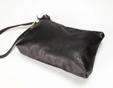 A black leather clutch bag with a matching wrist strap and small gold hardware, photographed on a plain white background.