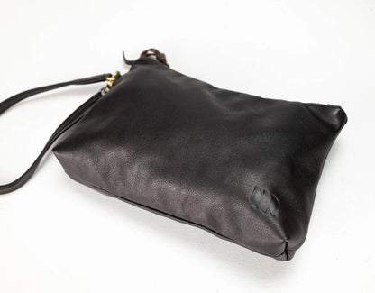 A black leather clutch bag with a matching wrist strap and small gold hardware, photographed on a plain white background.