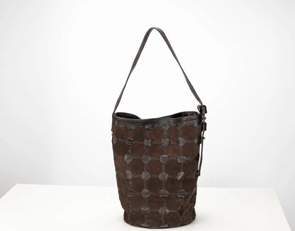 A dark brown leather bucket bag with a distinctive honeycomb pattern of stitched circular patches on the front, a black leather trim, and a single shoulder strap, set against a plain white background.