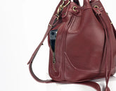 Burgundy leather handbag with a visible zipper pocket on a white background