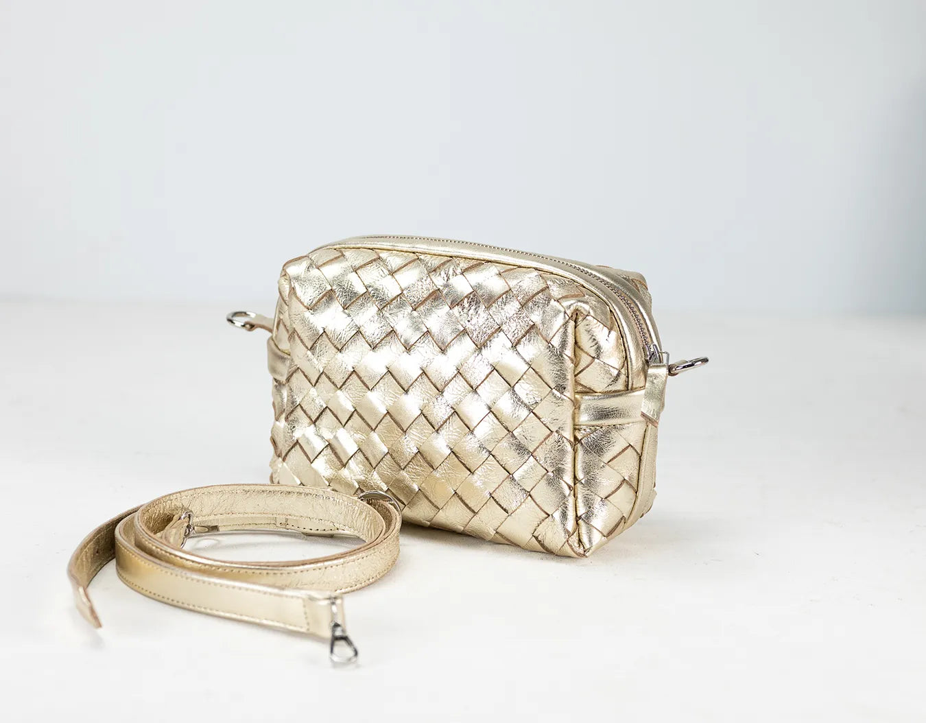 Gold woven handbag with a strap on a white background