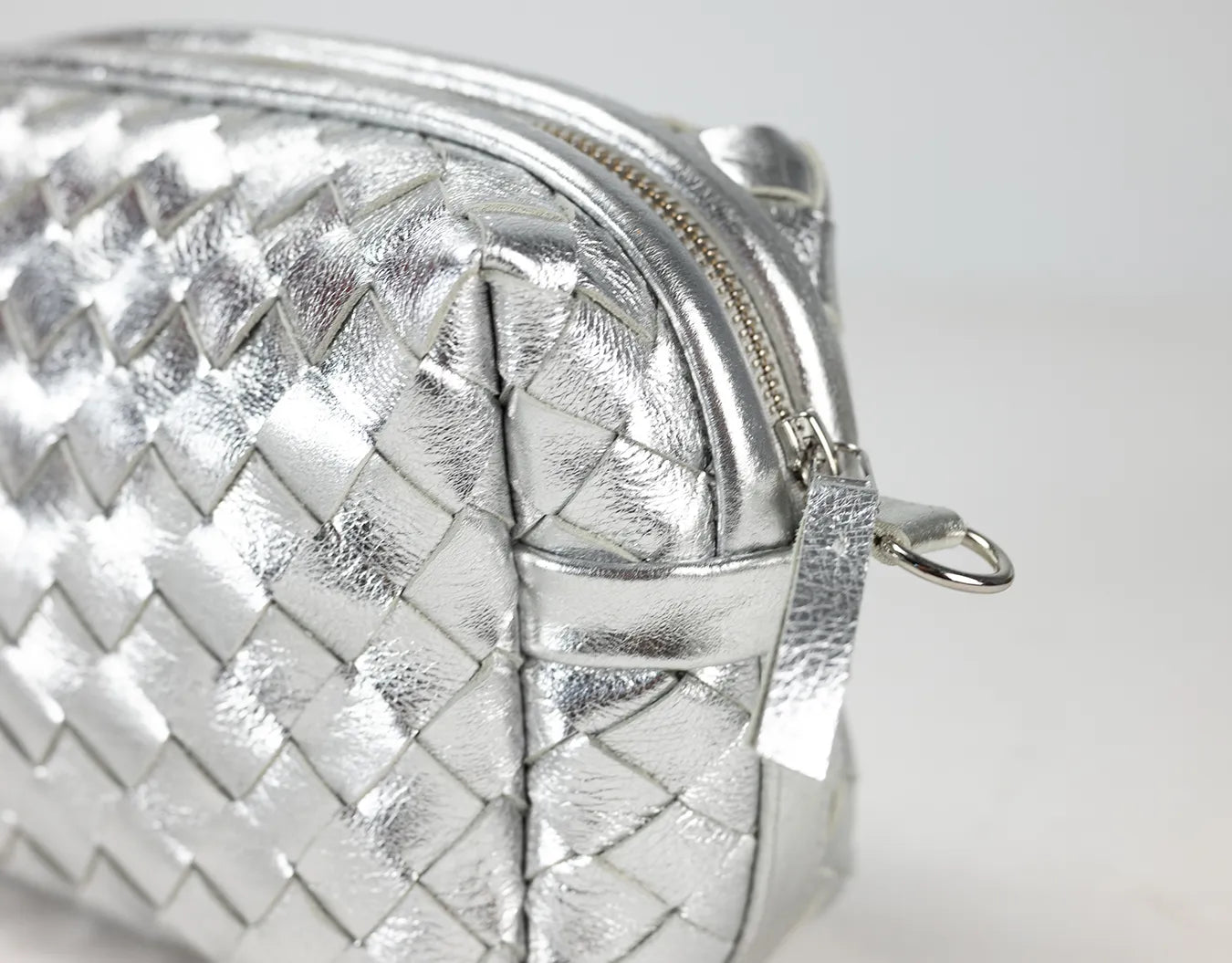 Silver woven clutch bag on a light gray background