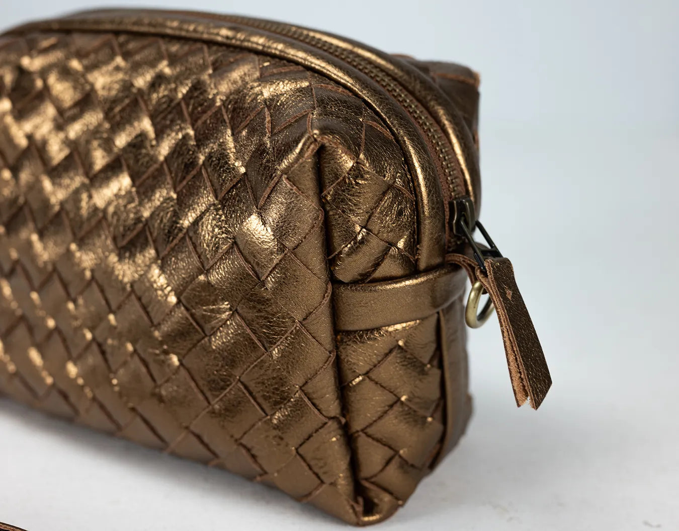 Bronze woven pouch with a zipper on a light gray background
