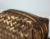 brass woven handbag with a textured pattern on a blurred background
