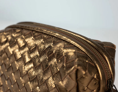 brass woven handbag with a textured pattern on a blurred background