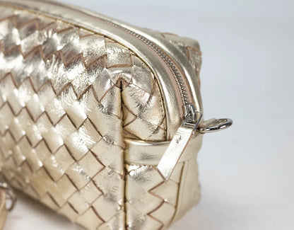 Gold woven handbag with a zipper on a light gray background