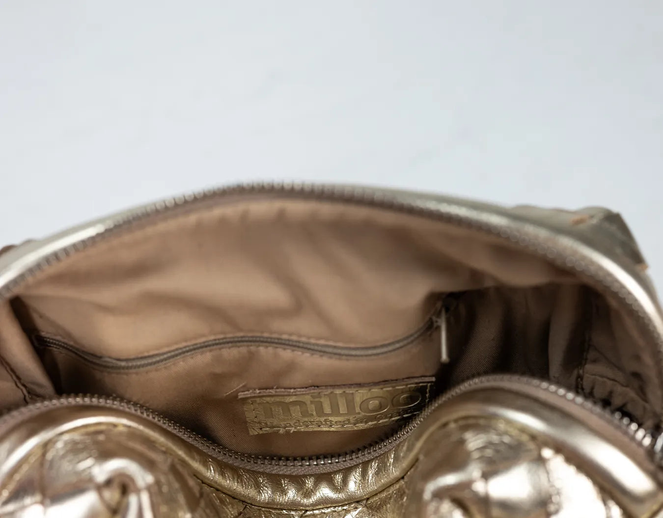 Gold handbag with visible brand logo on a light gray background