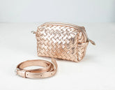Rose gold woven handbag and matching belt on a light gray background