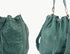 Green leather handbag with textured side and drawstring top on a white background