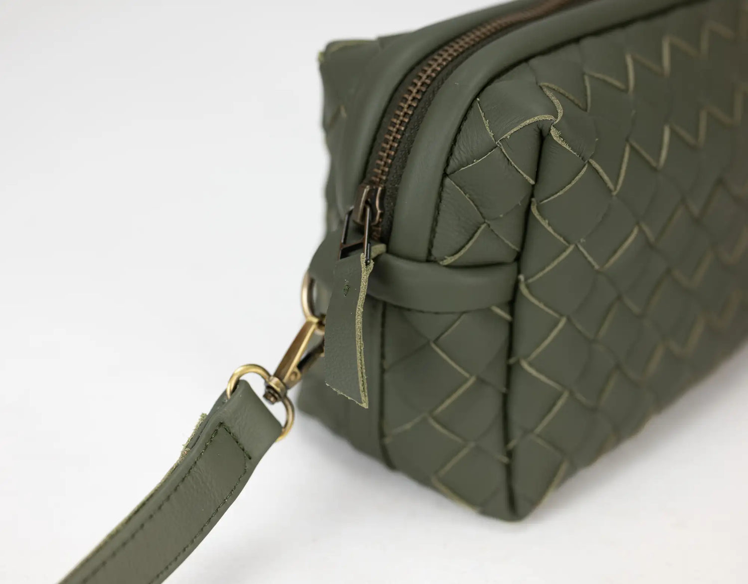 Green woven handbag with a gold zipper on a white background