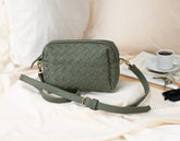 Green woven handbag on a light surface with a cup of coffee 