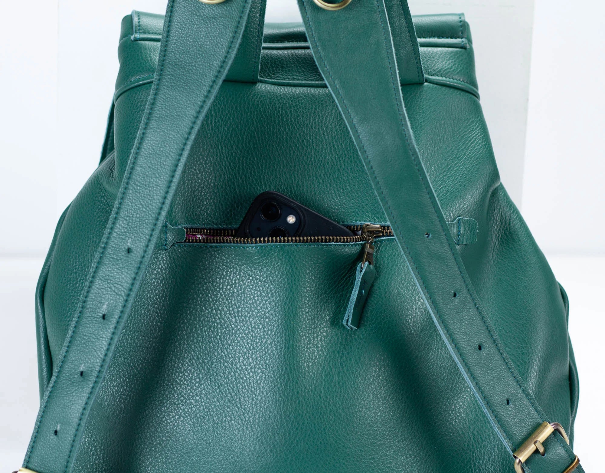 Green leather backpack with a zipper on a white background