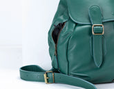 Green leather backpack with gold buckles on a white background