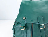 Green leather backpack with gold buckles on a light gray background