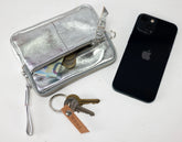 Silver wallet, keys, and black phone on a white background