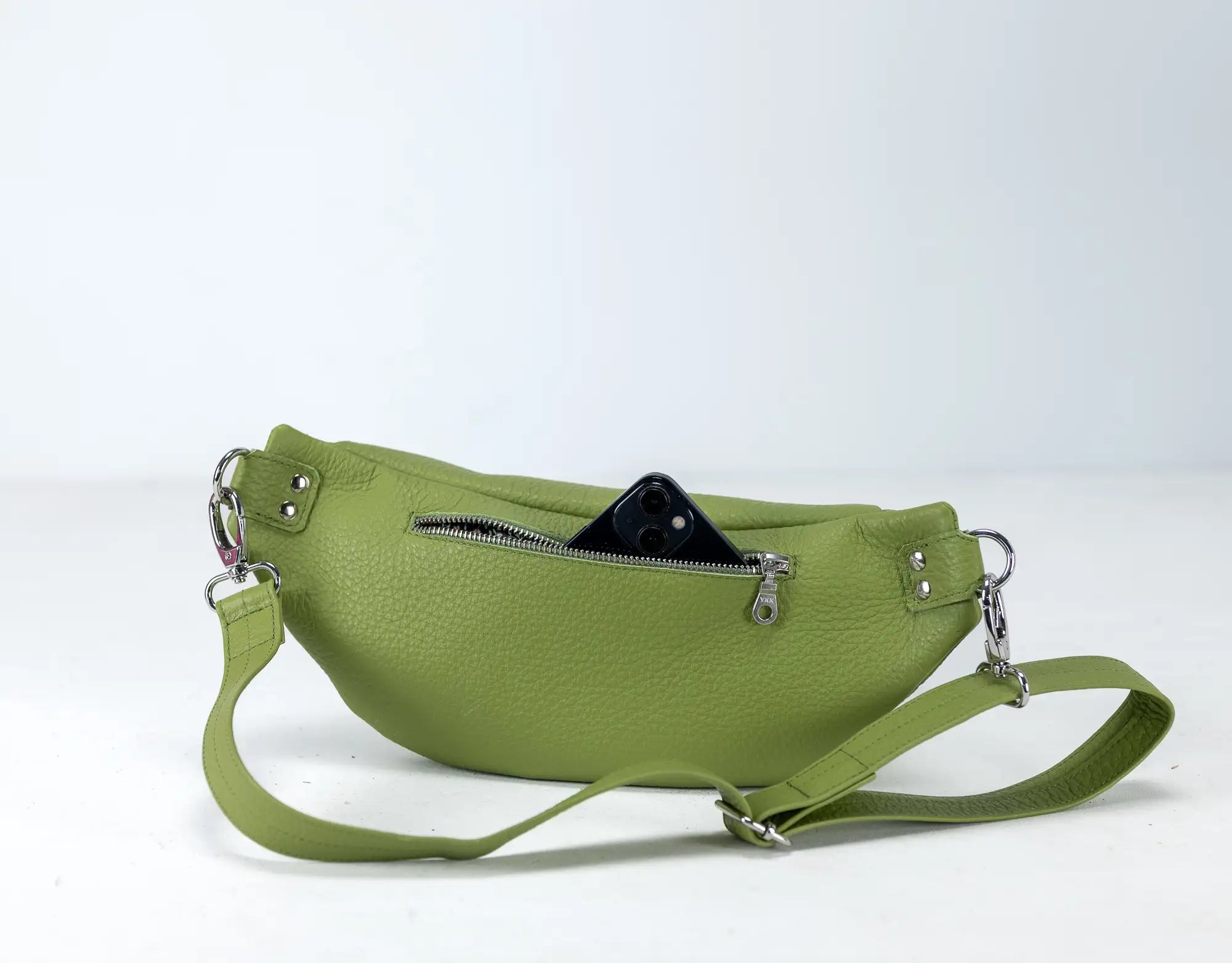 Green leather waist bag with a black phone case on a white background