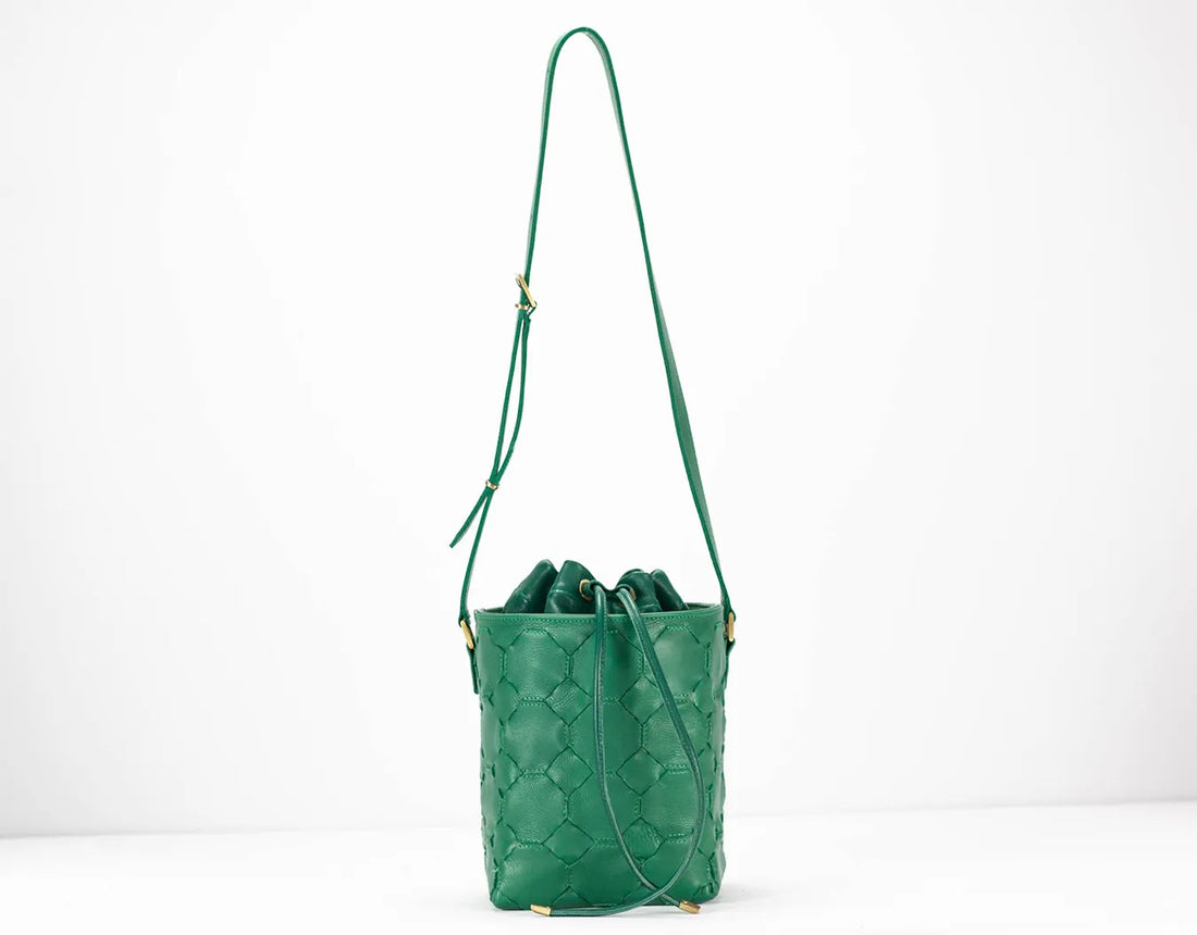 Green quilted handbag with a strap on a white background