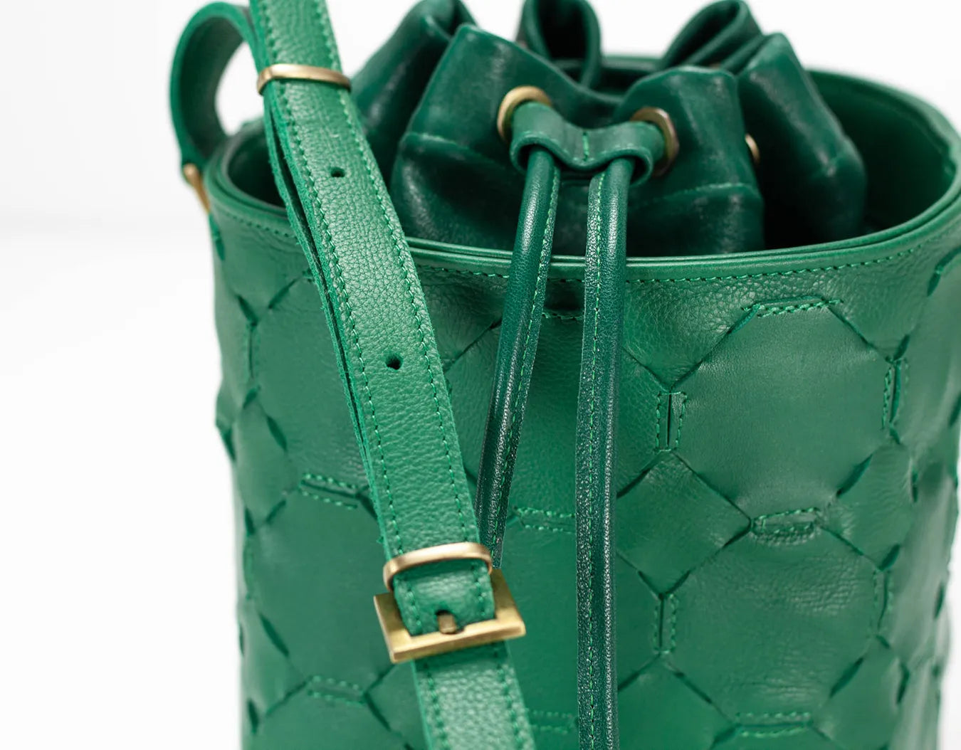 Green woven bucket bag with a strap on a white background