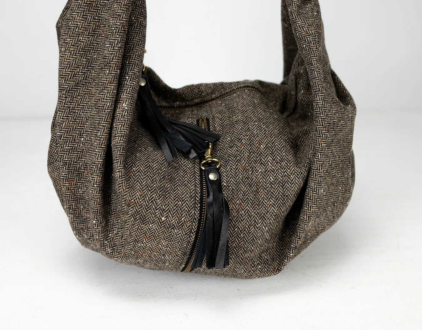 Brown textured handbag with a black zipper on a white background