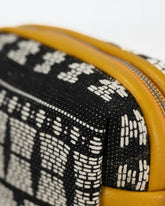 Close-up of a black and white patterned pouch with a yellow zipper.