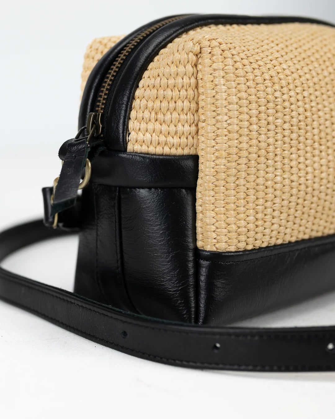 Woven bag with black leather accents on a white background