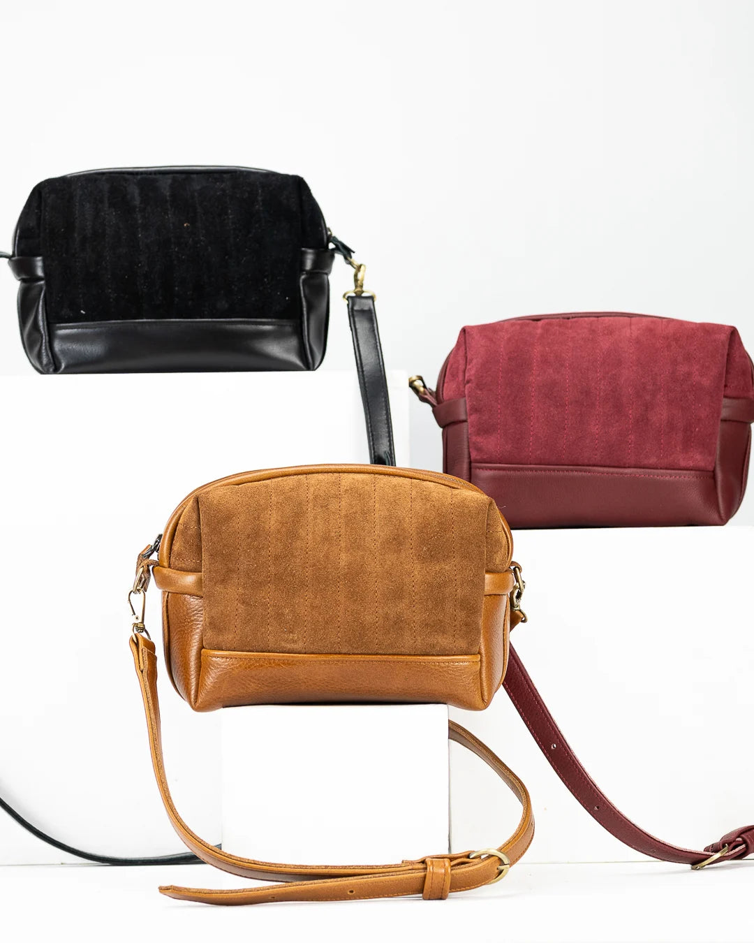 Three leather handbags in black, brown, and red on a white background