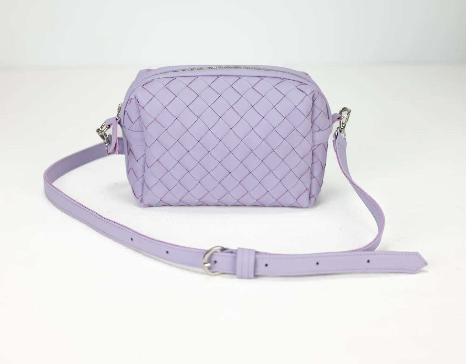 Lavender quilted handbag with a strap on a white background