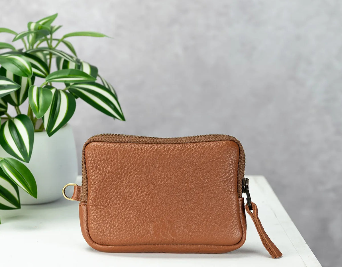 Brown leather wallet on a white surface with a plant in the background#color_brown